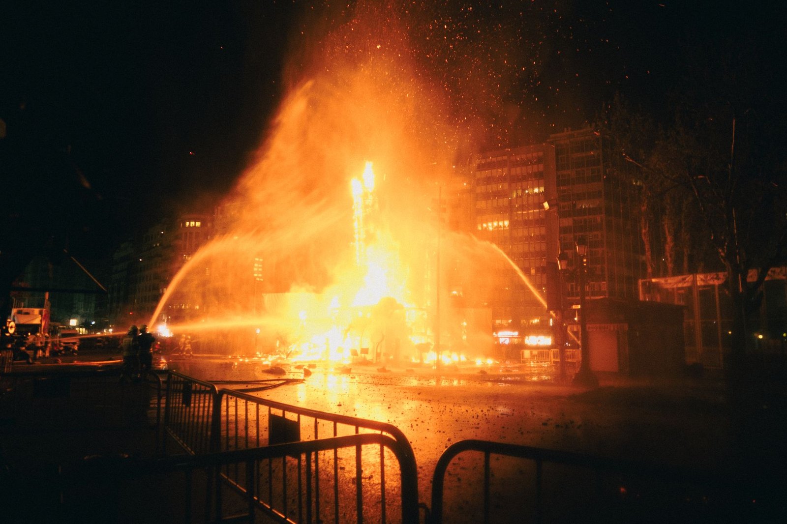 Monumentos falleros ardiendo de noche con fuegos artificiales durante la Cremà de las Fallas de Valencia