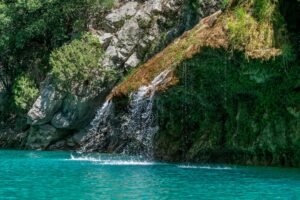 Cascada de agua turquesa cayendo entre rocas, similar a las barreras de toba que separan las lagunas de Ruidera