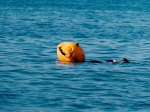 Nadador en aguas abiertas con una boya naranja brillante de seguridad