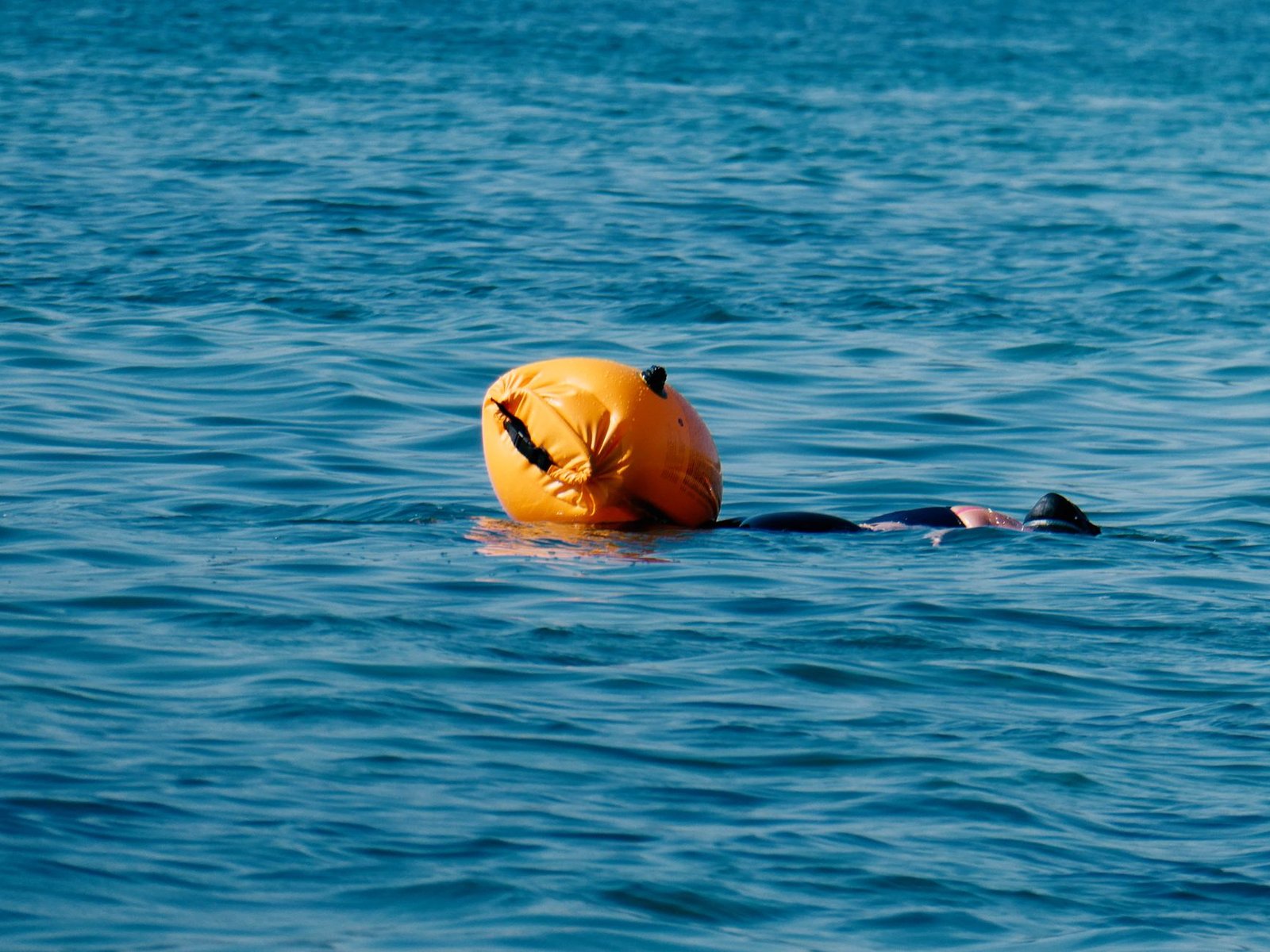 Nadador en aguas abiertas con una boya naranja brillante de seguridad