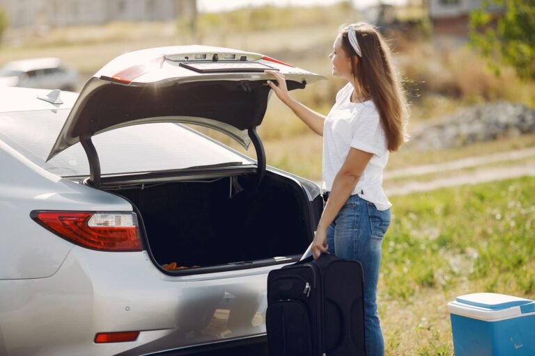Viajera colocando equipaje en el maletero abierto de un coche antes de una escapada