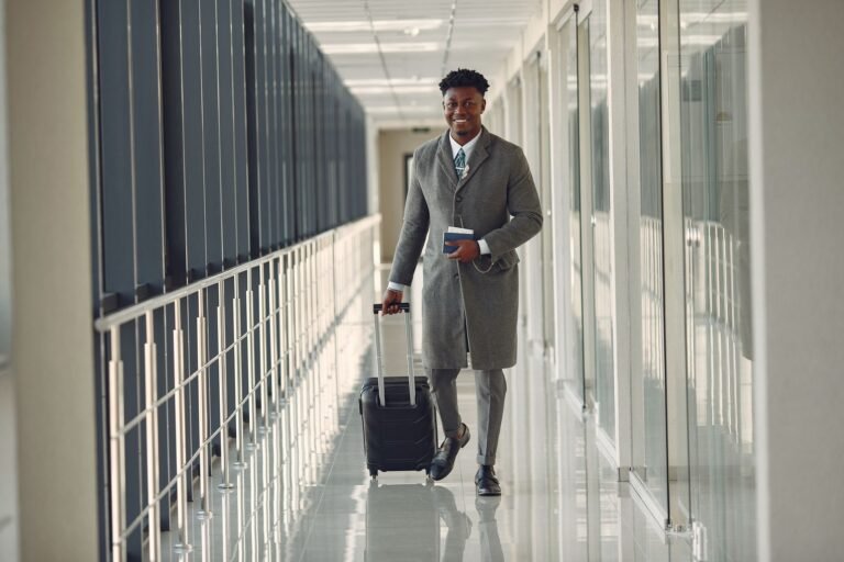 Viajero con traje y maleta de mano caminando por la terminal de un aeropuerto