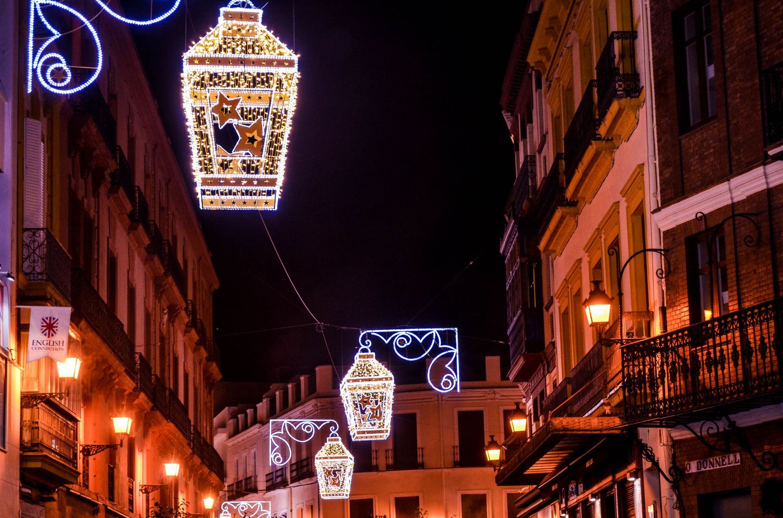 Calle de Sevilla iluminada de noche con farolillos durante la Feria de Abril