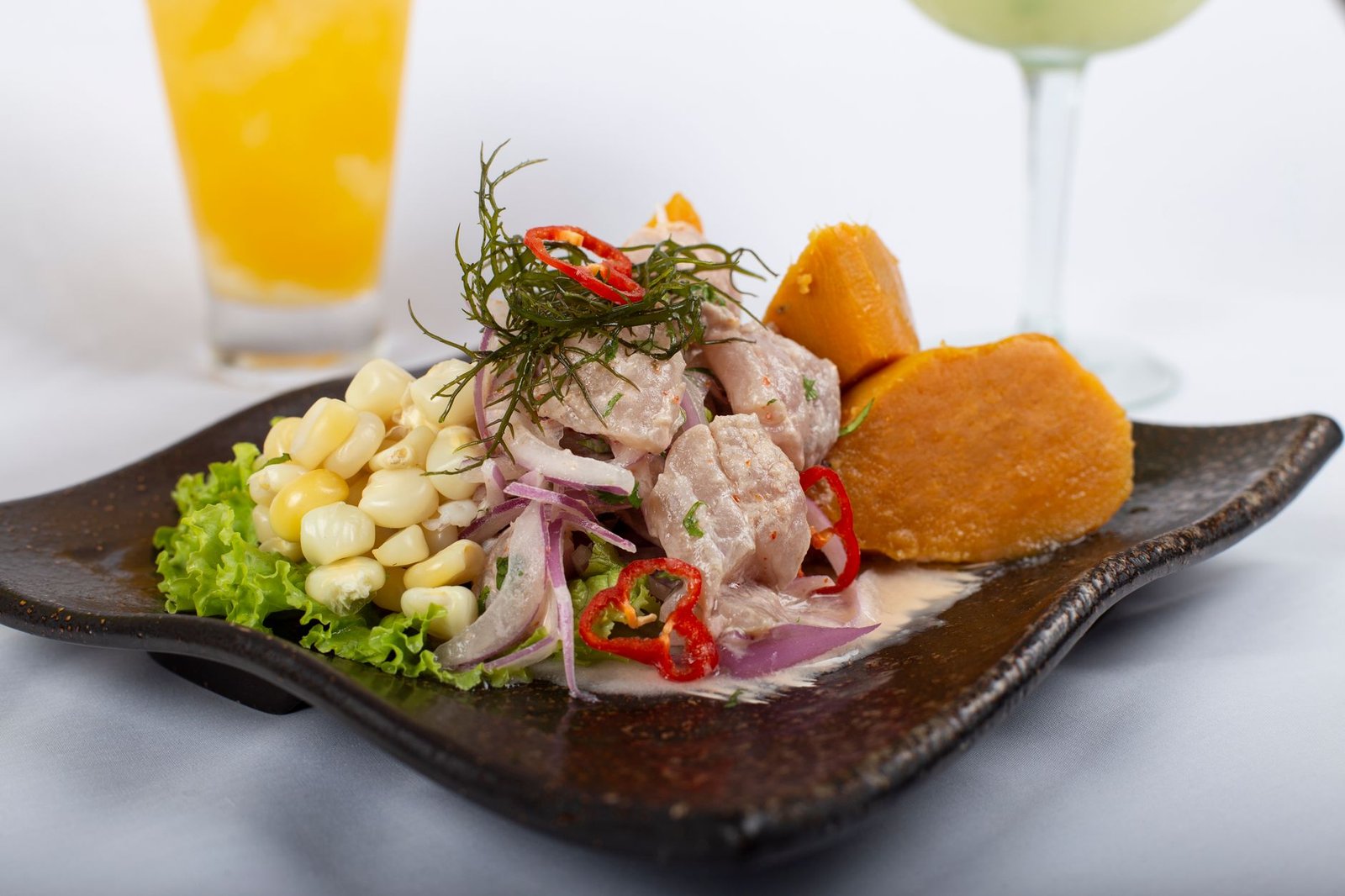 Ceviche peruano fresco con camote y choclo, típico de una cevichería en Lima
