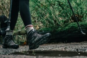Botas de senderismo salpicando en un charco de barro en un sendero de montaña