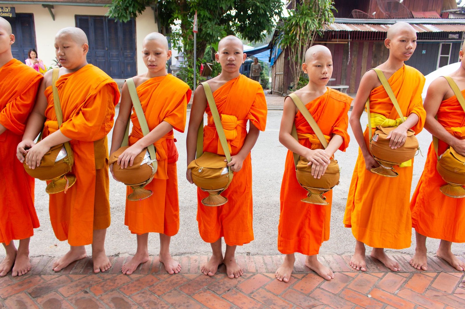 Jóvenes monjes con túnicas naranjas sosteniendo sus cuencos de limosna