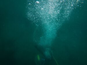 Buceador con botella de aire comprimido dejando un rastro de burbujas bajo el agua