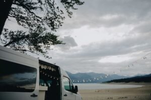 Furgoneta camper aparcada en una playa al atardecer, escenario típico de acampada