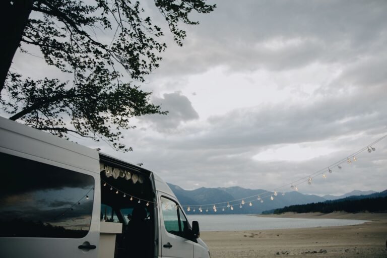 Furgoneta camper aparcada en una playa al atardecer, escenario típico de acampada