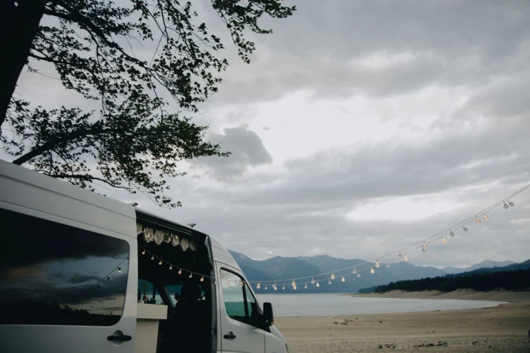 Furgoneta camper aparcada en una playa al atardecer, escenario típico de acampada