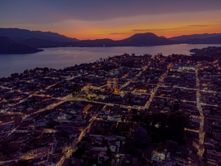 Vista aérea de Valle de Bravo al atardecer, con el pueblo iluminado junto al lago