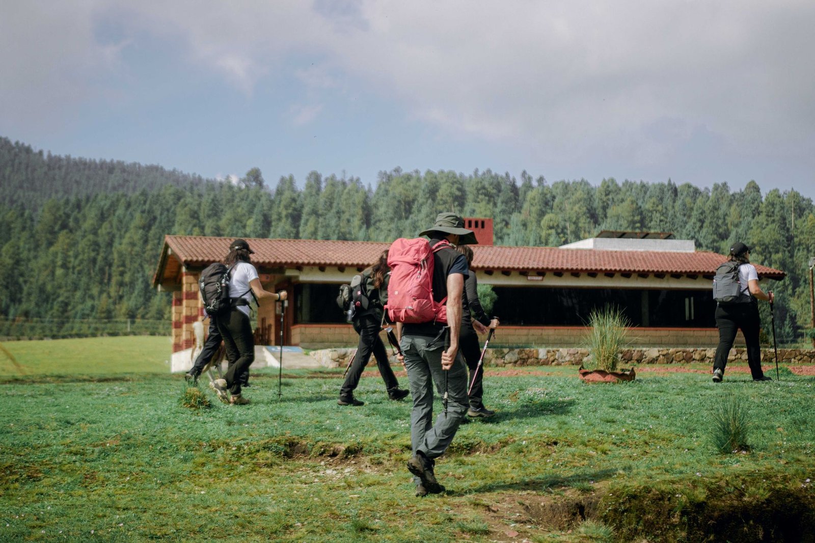 Excursionistas caminando junto a una cabaña rodeada de bosque cerca de Valle de Bravo