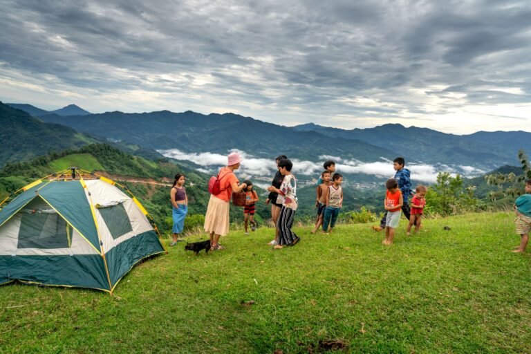 Niños jugando junto a una tienda de campaña familiar en la montaña