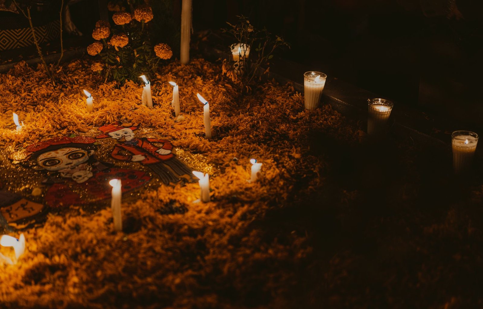 Alfombra de flores de cempasúchil con velas encendidas de noche durante el Día de Muertos
