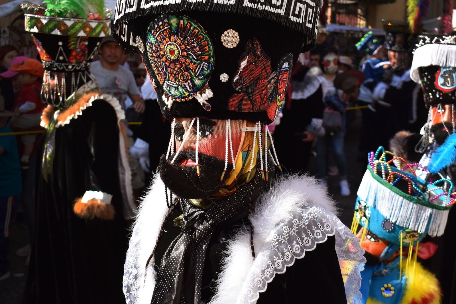 Participante con traje y tocado tradicionales en un desfile festivo en Tepoztlán