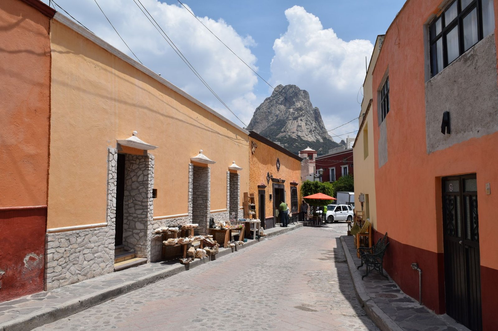 Calle empedrada de un pueblo de México con casas de colores y la Peña de Bernal al fondo