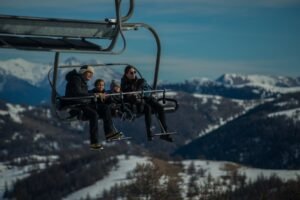 Familia disfrutando de un telesilla con montañas nevadas de fondo en un día soleado de invierno
