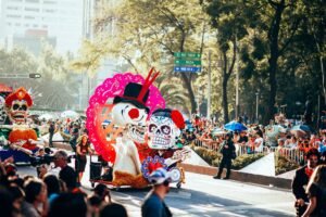 Desfile de Día de Muertos en las calles de la Ciudad de México, con esqueletos gigantes y carros alegóricos