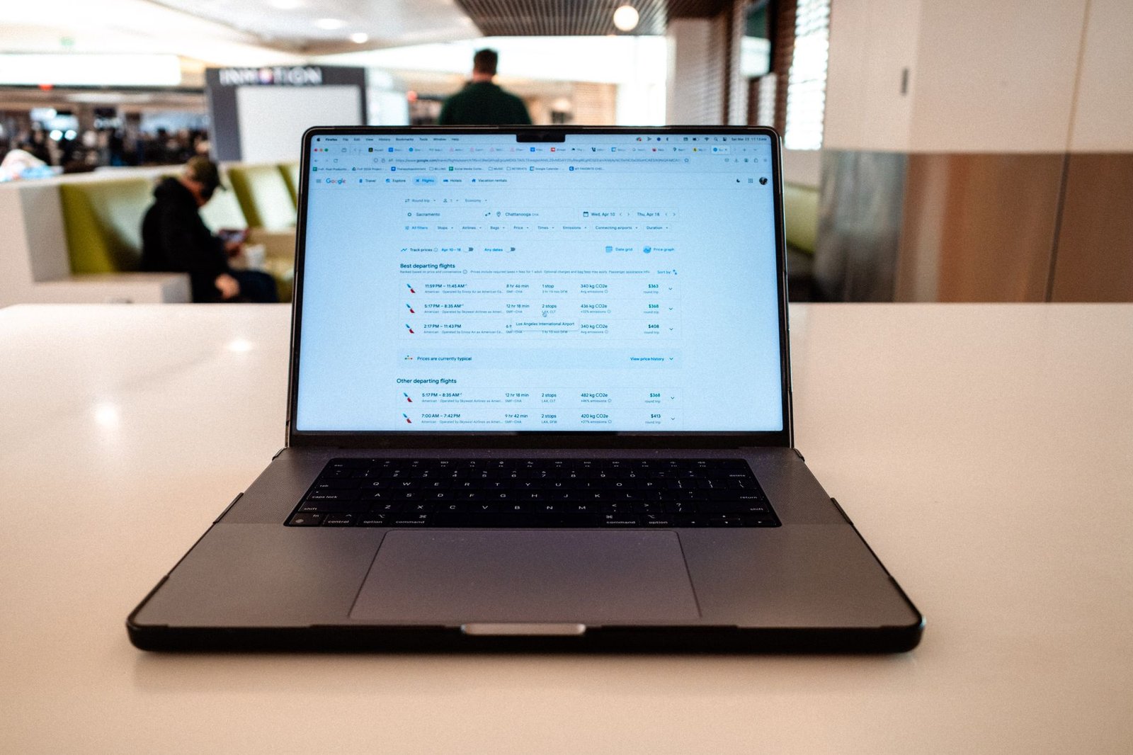 Portátil mostrando horarios de vuelos sobre una mesa en una sala de aeropuerto
