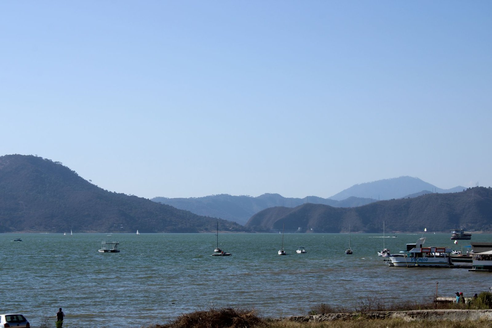 Barcas y veleros en el lago de Valle de Bravo con montañas al fondo