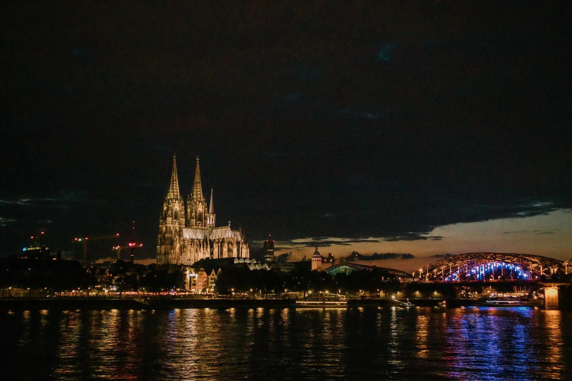 La catedral de Colonia y el puente Hohenzollern iluminados de noche sobre el Rin