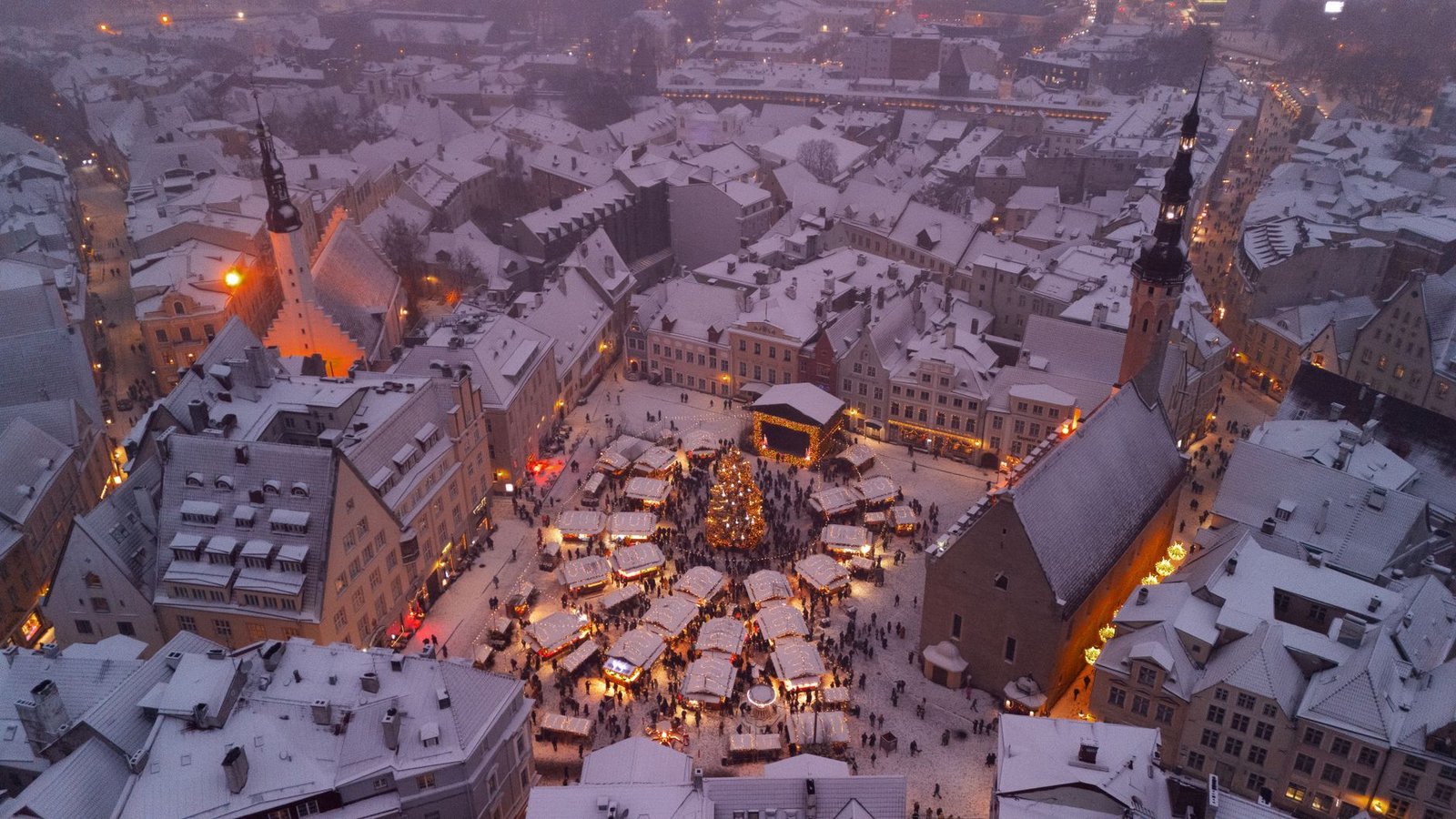Mercado de Navidad de Tallin visto desde arriba, con los puestos iluminados al atardecer