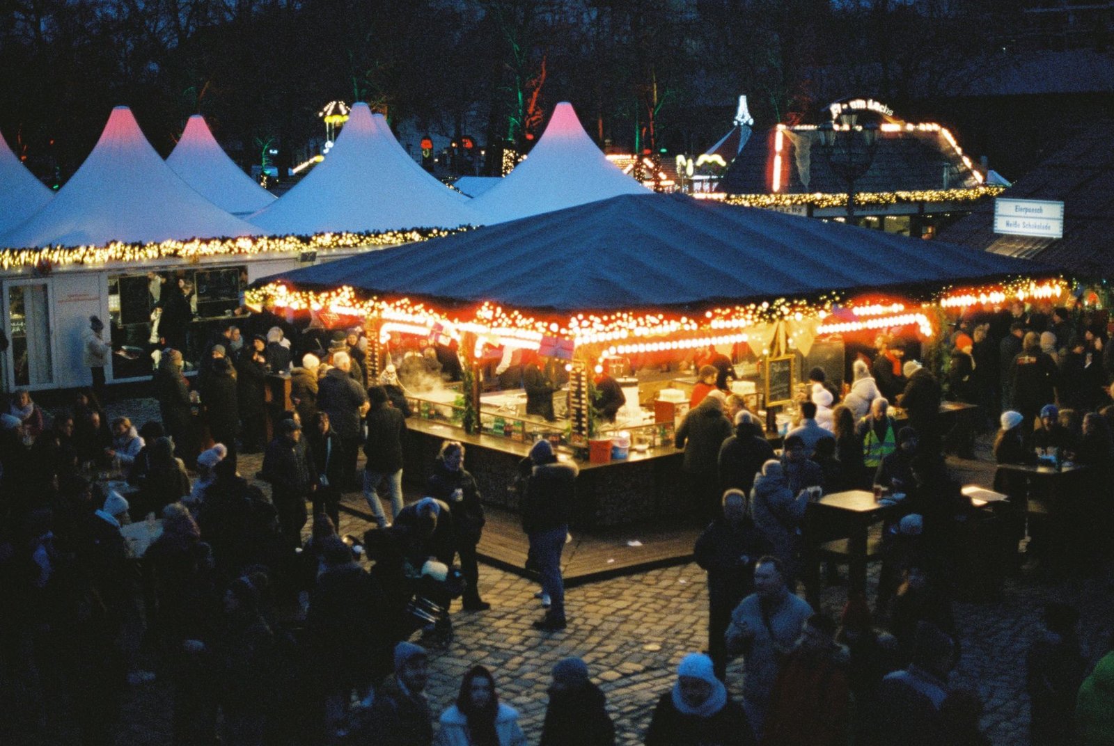 Mercado de Navidad concurrido de noche en Berlín, con luces y público