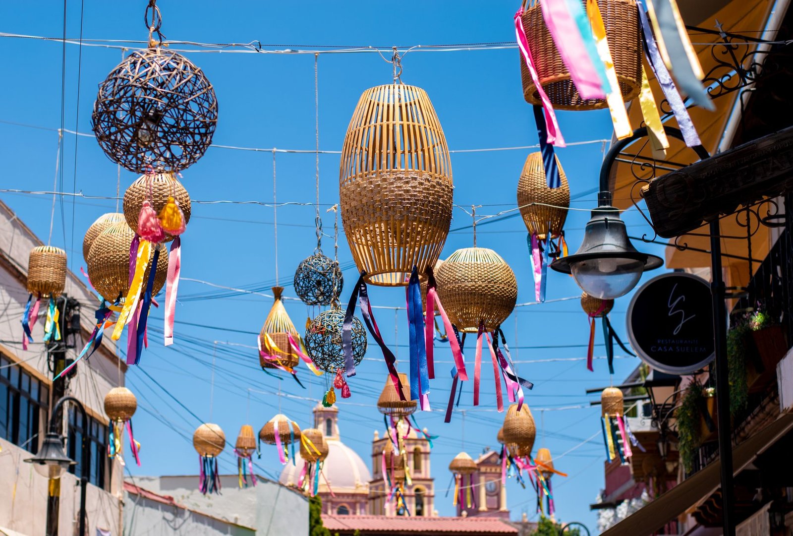 Farolillos de mimbre y listones de colores colgados sobre una calle de un pueblo de México