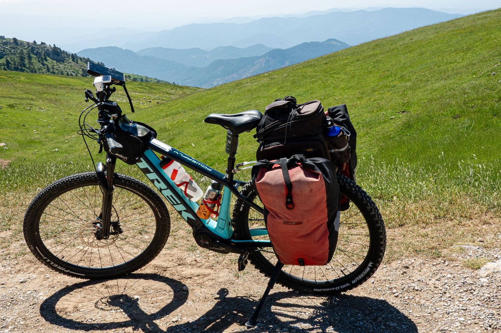 Bicicleta de montaña cargada con equipaje en una ladera con montañas al fondo