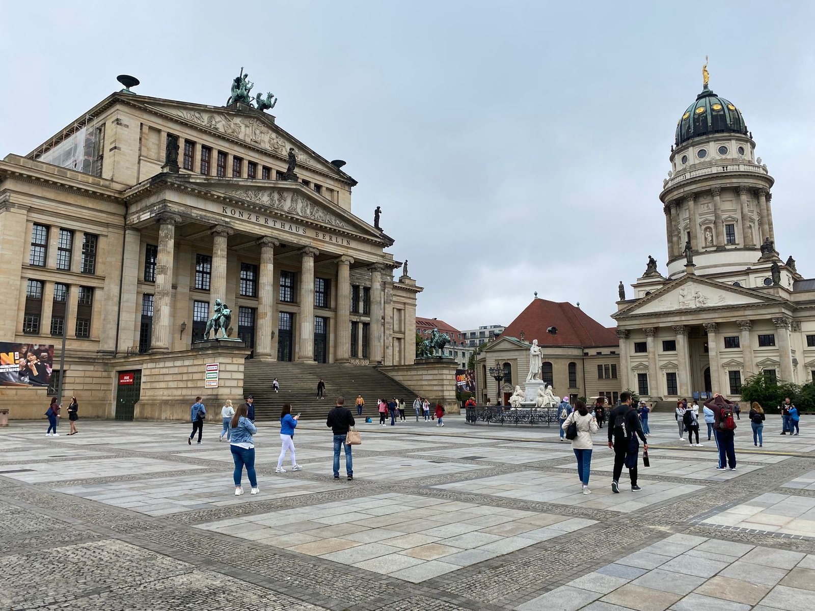 Turistas en la plaza Gendarmenmarkt de Berlín con la sala de conciertos y la catedral francesa