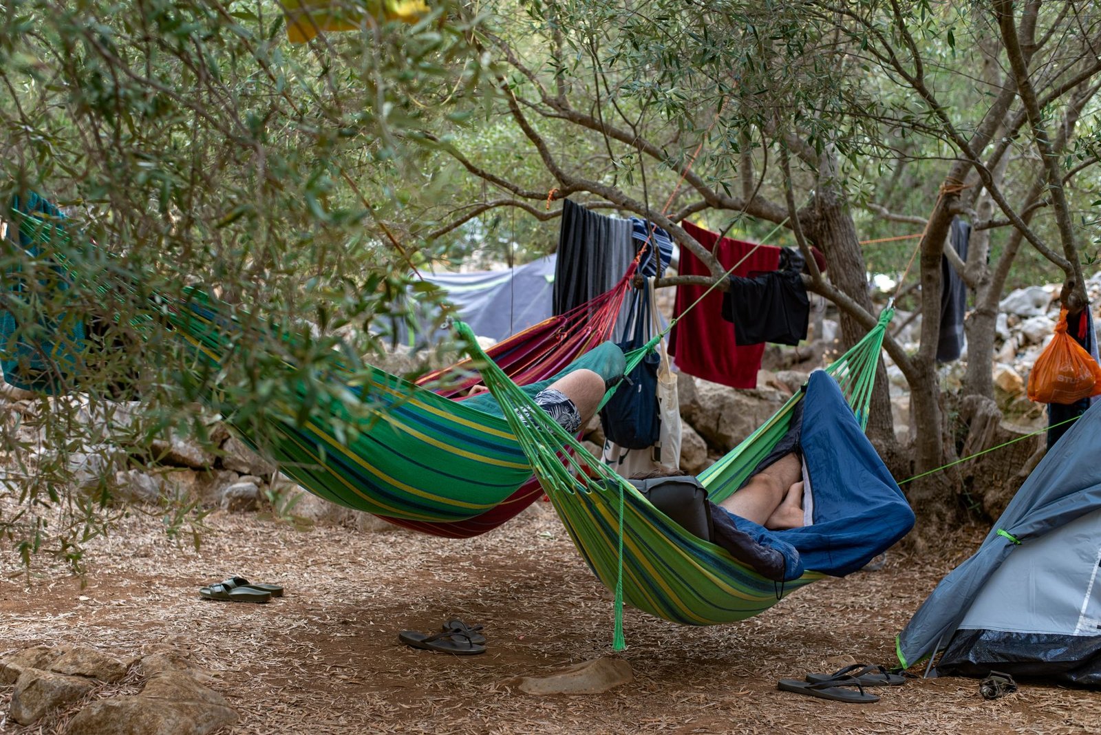 Campistas relajándose en hamacas con mosquitera entre los árboles de un camping