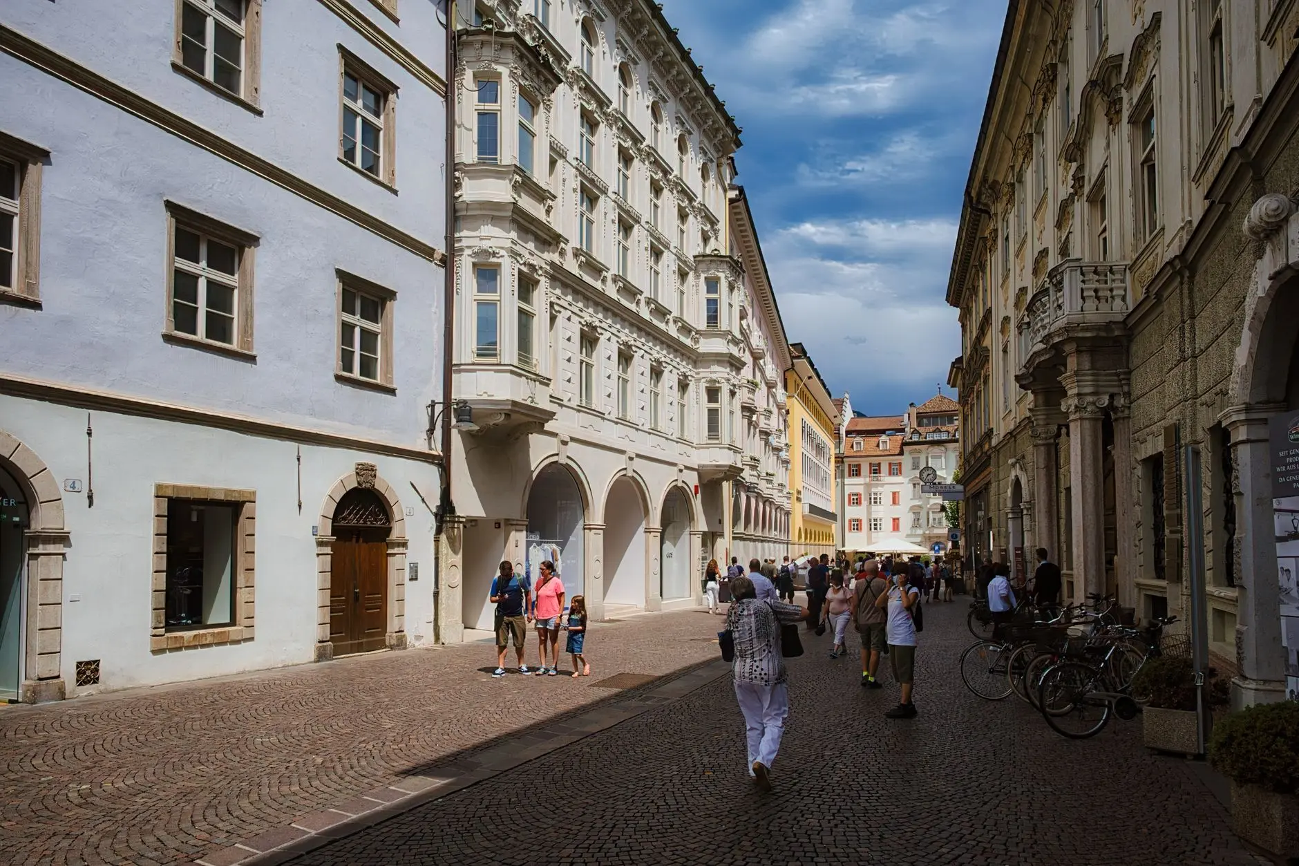 Calle adoquinada del centro histórico de Bolzano con edificios antiguos y peatones