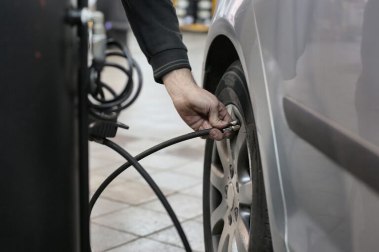 Mecánico inflando el neumático de un coche con un compresor