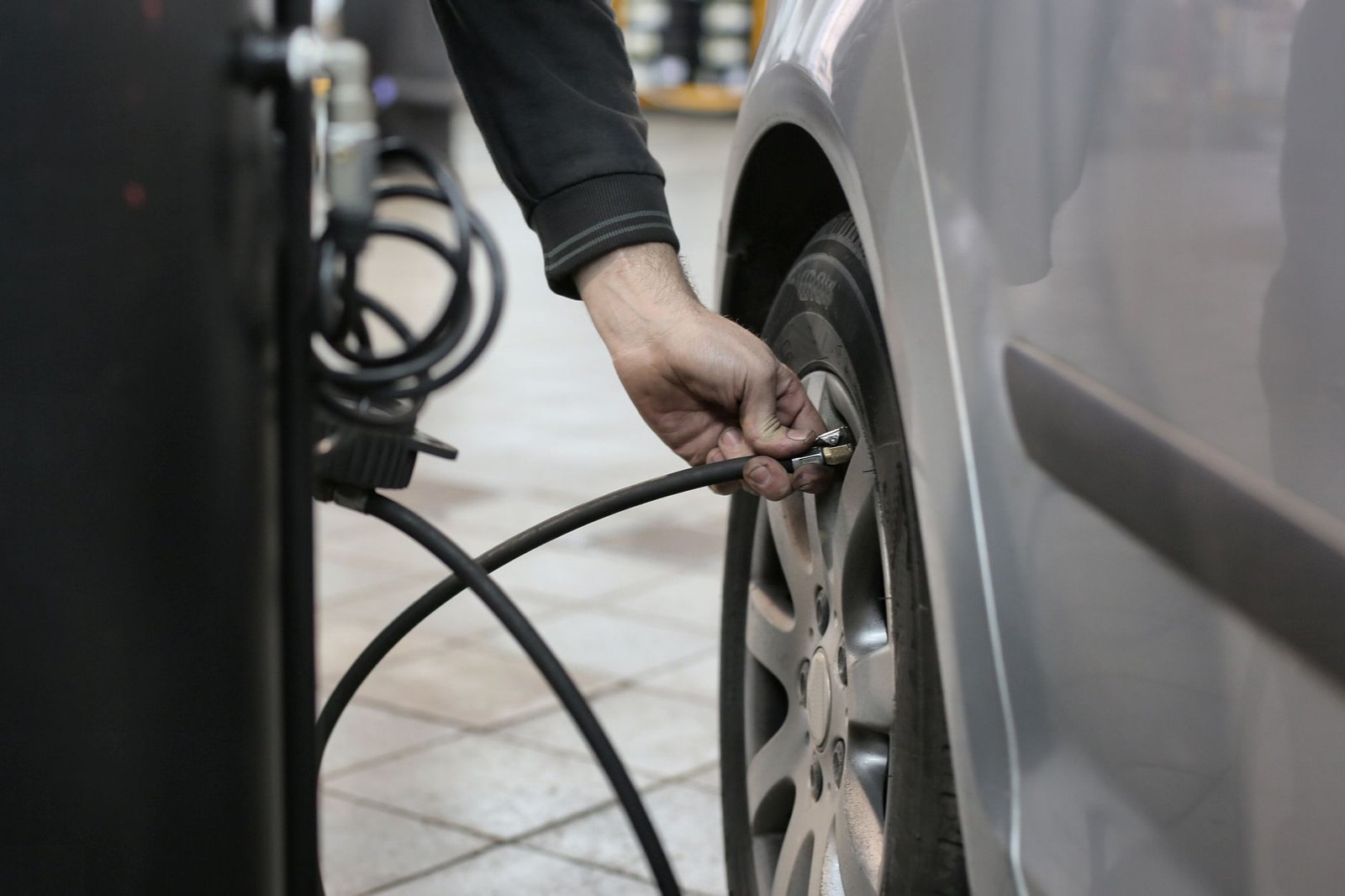 Mecánico inflando el neumático de un coche con un compresor
