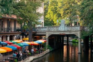 Terrazas con sombrillas de colores junto al canal del River Walk de San Antonio, Texas