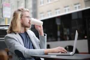 Joven trabajando en remoto con un portátil en la terraza de una cafetería