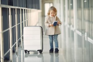 Niña con maleta de ruedas comprobando el billete en el aeropuerto