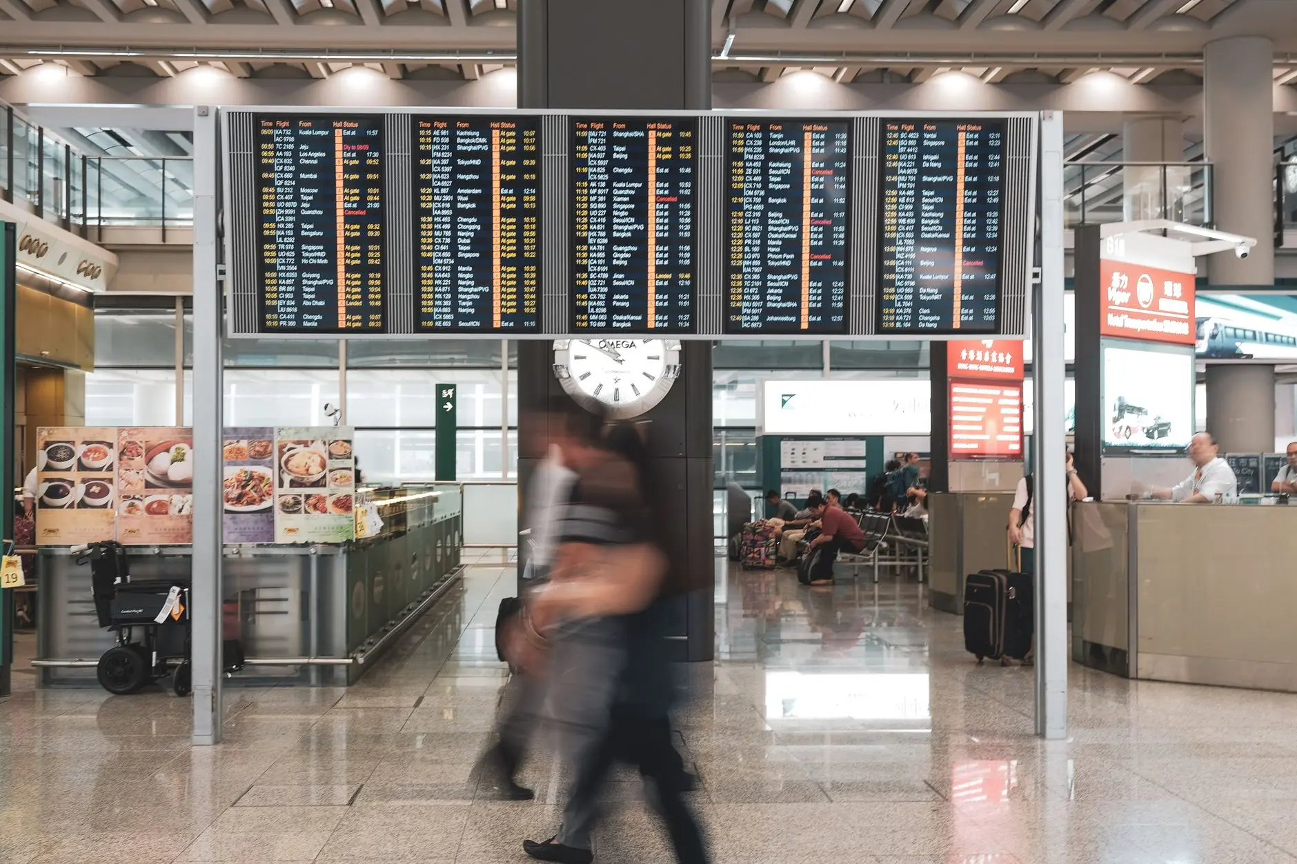 Viajeros en movimiento en un aeropuerto moderno con pantallas de salidas